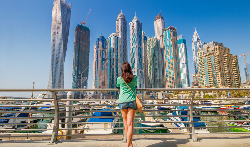 Female Tourist standing in front of skyscrapers in UAE