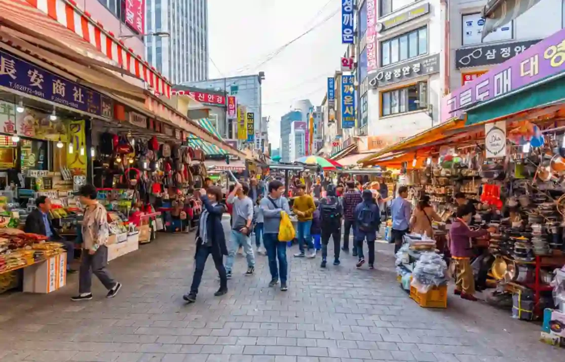 A vibrant street in Seoul with bustling crowds, colorful shops, and a peaceful ambiance, symbolizing normalcy and tourism activity.