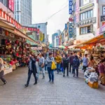 A vibrant street in Seoul with bustling crowds, colorful shops, and a peaceful ambiance, symbolizing normalcy and tourism activity.